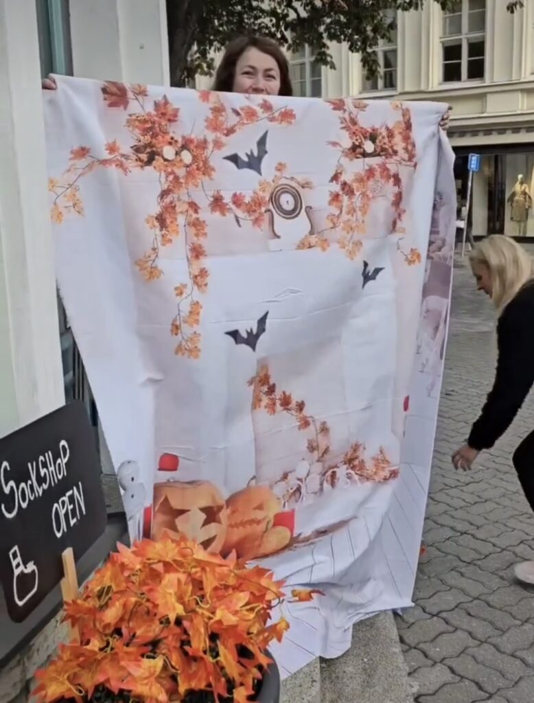 Team setting up a Halloween-themed window display at Sokisahtel, featuring spooky socks and decorations.