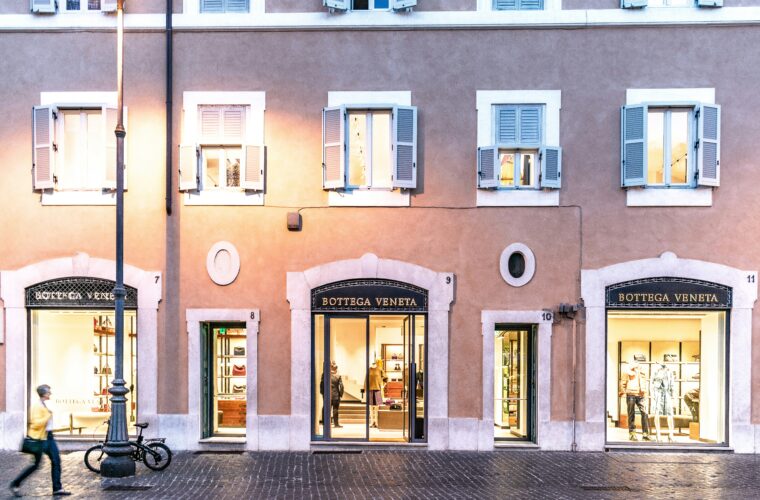 Botega Veneta poe fassaad ajaloolises linnatänavas õhtusel ajal, avatud akende ja vitriinidega.