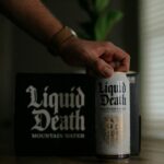 Person picking up a can of Liquid Death mountain water in a well-lit room