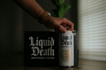 Person picking up a can of Liquid Death mountain water in a well-lit room