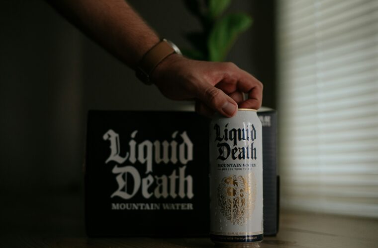 Person picking up a can of Liquid Death mountain water in a well-lit room