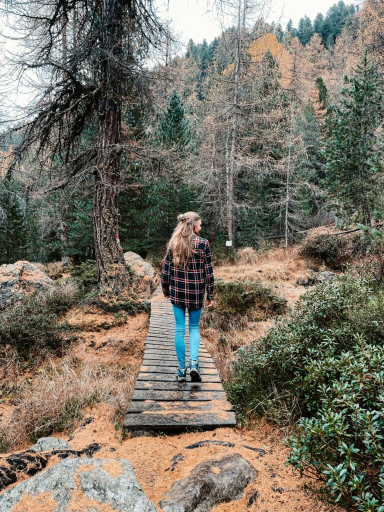 Me explores a wooden trail through a serene forest with autumn hues and rugged terrain
