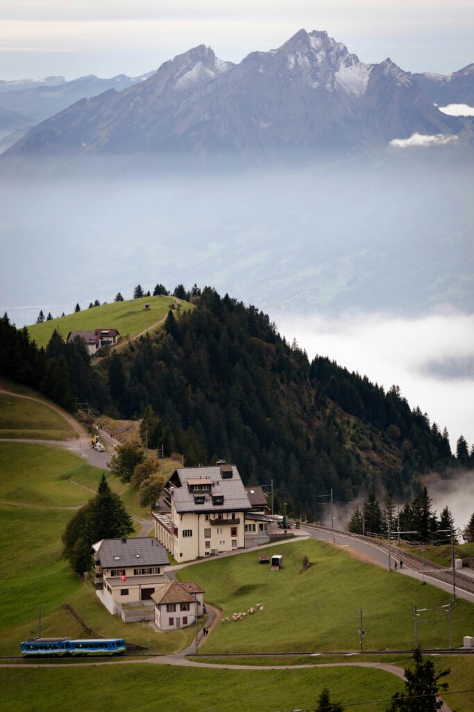 Scenic Swiss Alps with a charming mountain village and a colorful train, framed by lush greenery and misty peaks