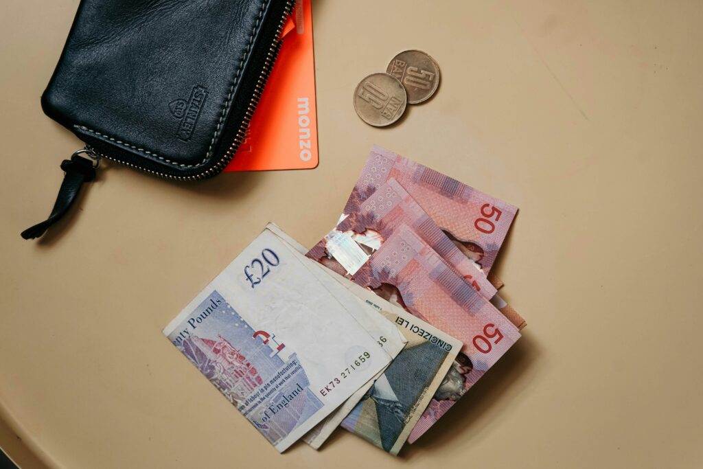 Overhead view of a black wallet, a Monzo card, banknotes, and two coins.