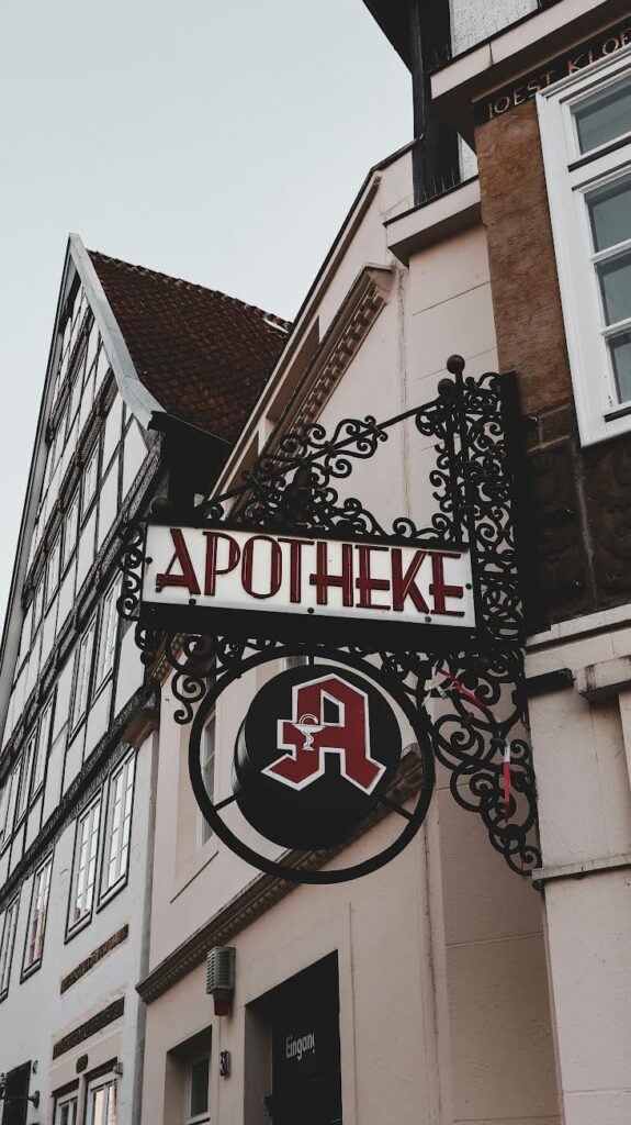 An ornate wrought-iron "Apotheke" sign hanging from a traditional European building.